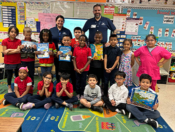 Two WSSC Water employees posing with a group of school children in a classroom.